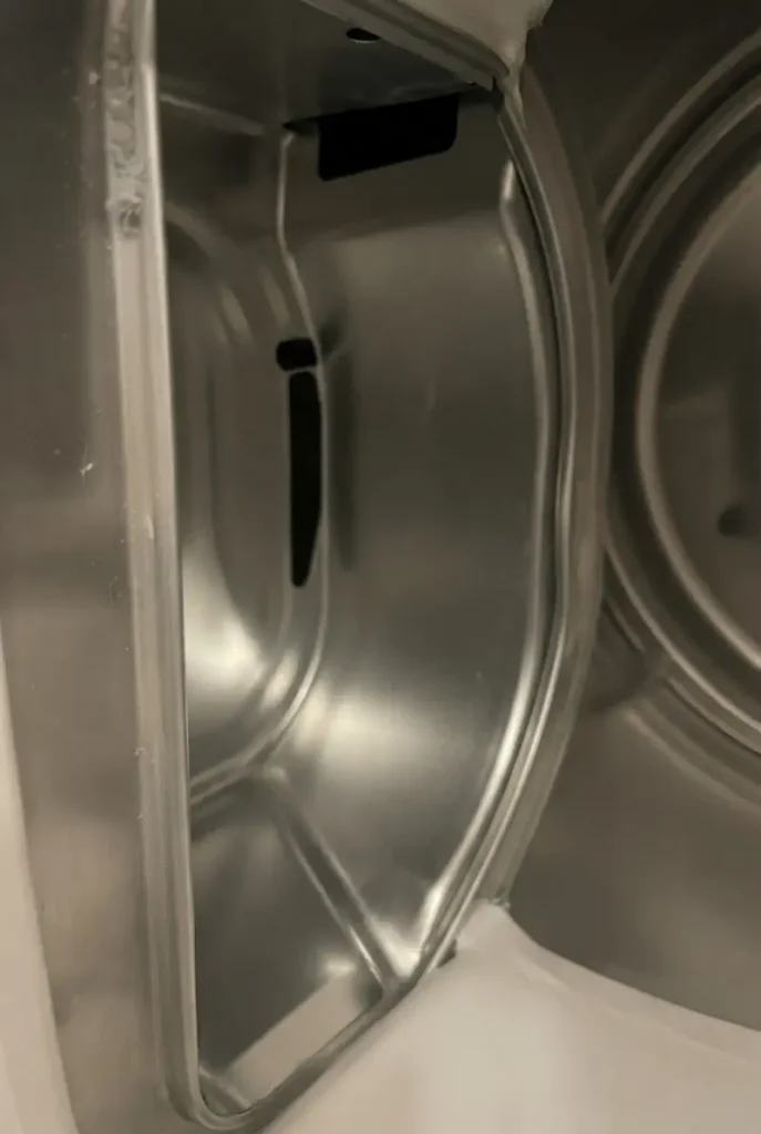 Inside view of a clean stainless steel dryer drum and unobstructed lint trap housing.