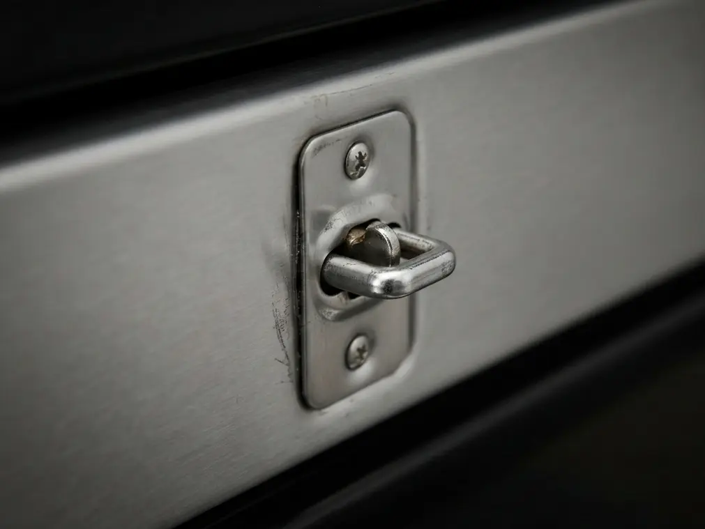 Close-up of a Whirlpool oven door latch stuck tightly shut due to a mechanical or thermal fuse fault.